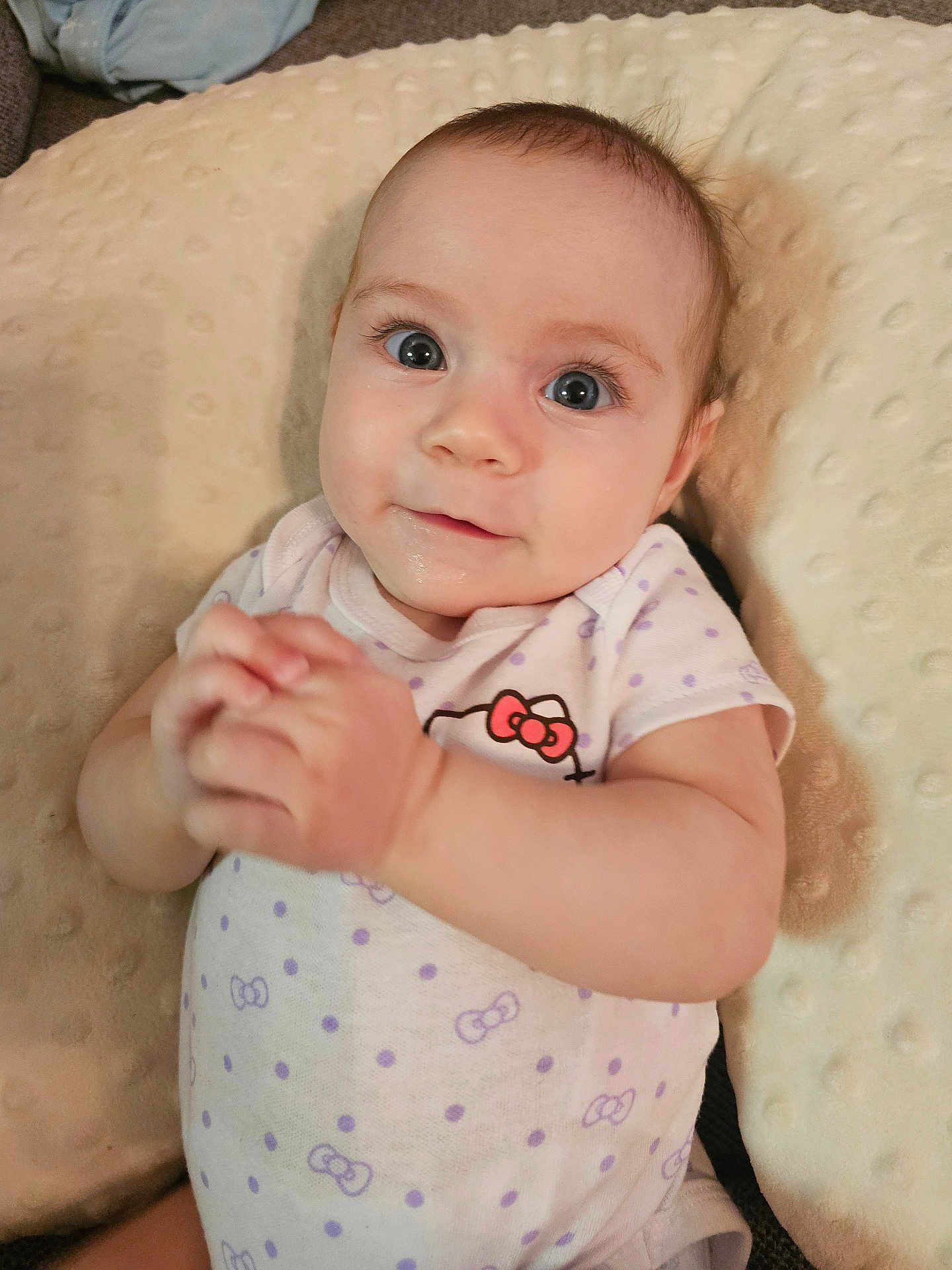 Lyla joined the competition — help win amazing prizes! baby, infant, child, face, hands, onesie, polka_dots, hello_kitty, cushion, soft_texture, indoor, portrait, cute, smile, wide_eyes, skin, sleepwear, lying_down, young, person