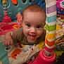 Lyla is registered to the contest to win money with this photo: baby, tongue_out, play_mat, colorful, toy, striped, play_gym, infant, child, smiling, cute, indoors, floor, bright, happy, person, face, fun, closeup, tummy_time