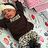 baby, infant, child, portrait, lying_down, floral_blanket, bow_headband, black_shirt, leopard_print, fashion, smiling, open_mouth, face, eyes, indoor, nursery, changing_mat, pink_blanket, clothing, photography