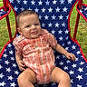 Waylon is registered to the contest to win money with this photo: baby, blue_chair, buttoned_clothing, child, cute, grass, happy, infant, onesie, orange_clothing, outdoor, person, plaid, portrait, relaxed, seated, smiling, star_pattern, summer, tongue_out