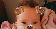 Alice is registered to the contest to win money with this photo: baby, child, face_filter, dog_ears, butterflies, blanket, cozy, indoor, person, infant, cute, portrait, smiling, soft_lighting, closeup, family, parent, childhood, warmth, comfort