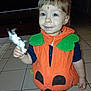 toddler, child, pumpkin_costume, orange, green, toy, zebra, indoor, tile_floor, cute, face, person, clothing, earrings, happy, smile, short_hair, living_room, home, floor