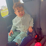 Isaac a rejoint le concours — aidez-le/la à gagner de superbes lots ! child, car_seat, vehicle_interior, curly_hair, casual_clothing, seatbelt, window, red_object, young_child, looking_at_camera, car_seat_booster, indoor, sitting, seat, curious_expression, daylight, casual, young_person, car, transportation