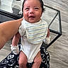 Kross joined the competition — help win amazing prizes! baby, infant, smiling, bib, mittens, white_clothing, adult_arm, holding, mohawk_hairstyle, indoor, glass_table, wooden_floor, blanket, heart_pattern, happy, person, cute, portrait, child, young
