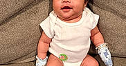 Kross is registered to the contest to win money with this photo: baby, infant, onesie, mittens, couch, brown_couch, seated, happy, smiling, indoor, person, child, cute, furniture, comfortable, portrait, young, skin, hair, expression