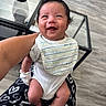 Kross is registered to the contest to win money with this photo: baby, smiling, infant, bib, clothing, person, indoor, happy, hair, hand, table, glass, floor, furniture, holding, skin, legs, foot, adult, casual