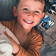 étann participe au concours pour gagner de l'argent avec cette photo : child, smiling, blanket, couch, clothing, person, face, happy, toddler, indoors, fabric, textile, casual, toy, home, cozy, portrait, sleeve, comfort, cute