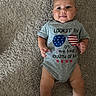 baby, infant, carpet, onesie, smile, face, child, laying_down, celebration, clothing, cute, happy, person, skin, leg, foot, hand, indoor, photography, portrait