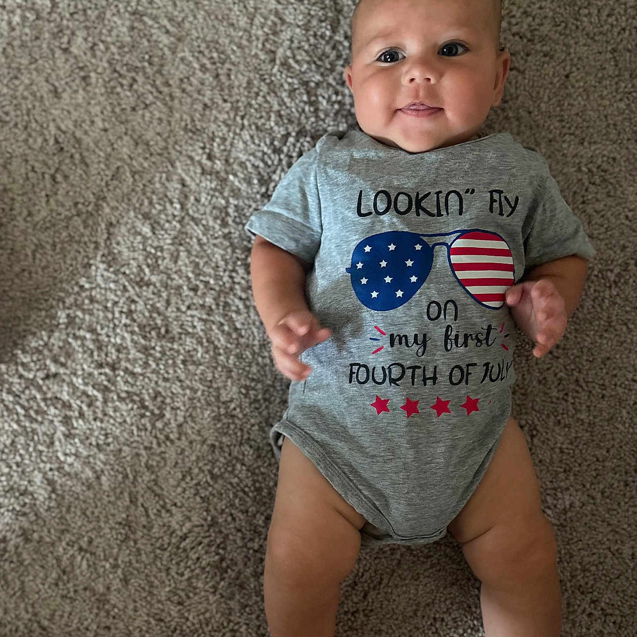 Cameron is registered to the contest to win money with this photo: baby, infant, carpet, onesie, smile, face, child, laying_down, celebration, clothing, cute, happy, person, skin, leg, foot, hand, indoor, photography, portrait