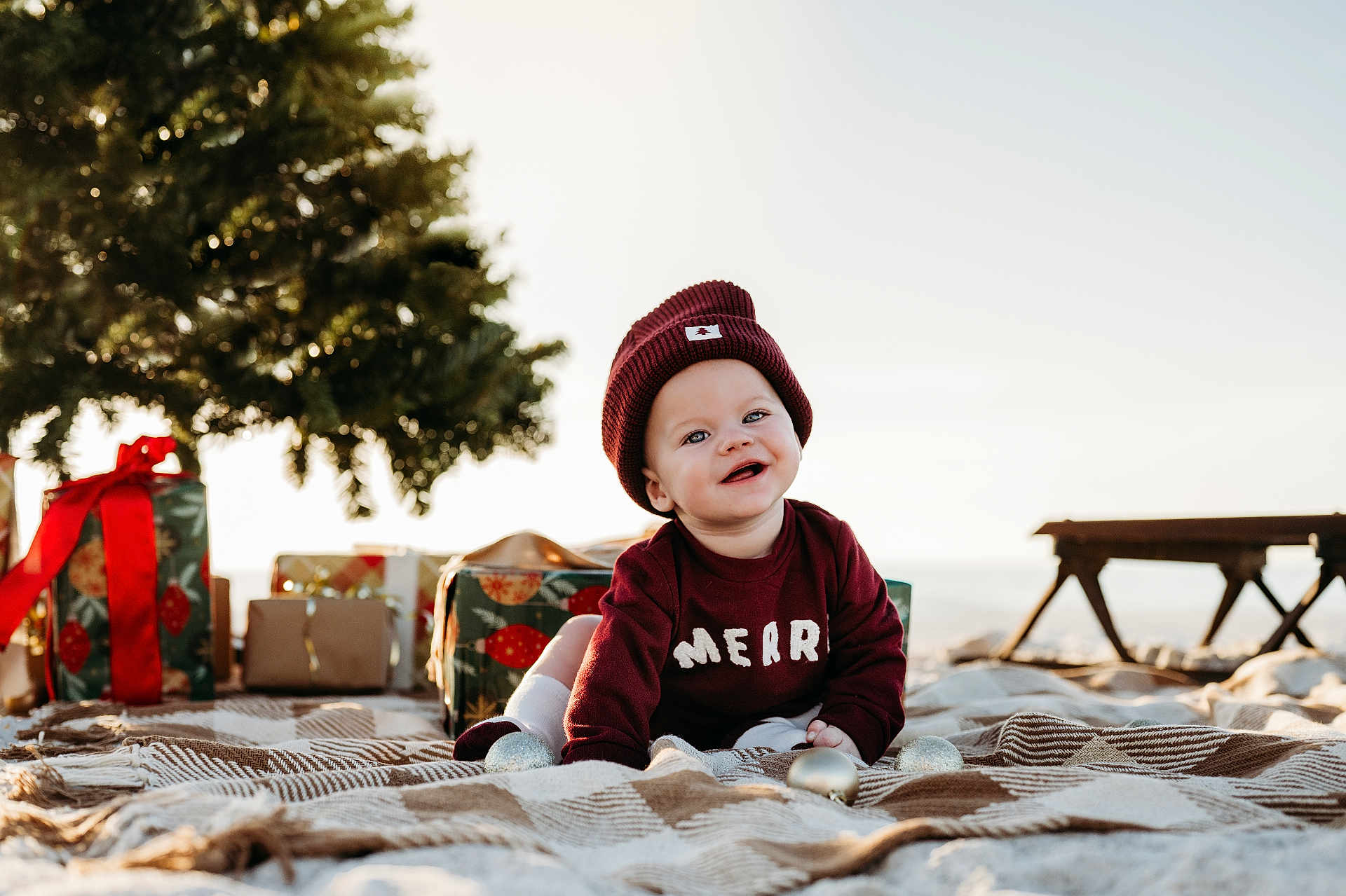 Jaxon joined the competition — help win amazing prizes! baby, smiling, maroon_clothing, beanie, blanket, outdoor, holiday, christmas_tree, gifts, festive, crawling, child, happy, toy, decorations, nature, sunlight, portrait, cute, seasonal