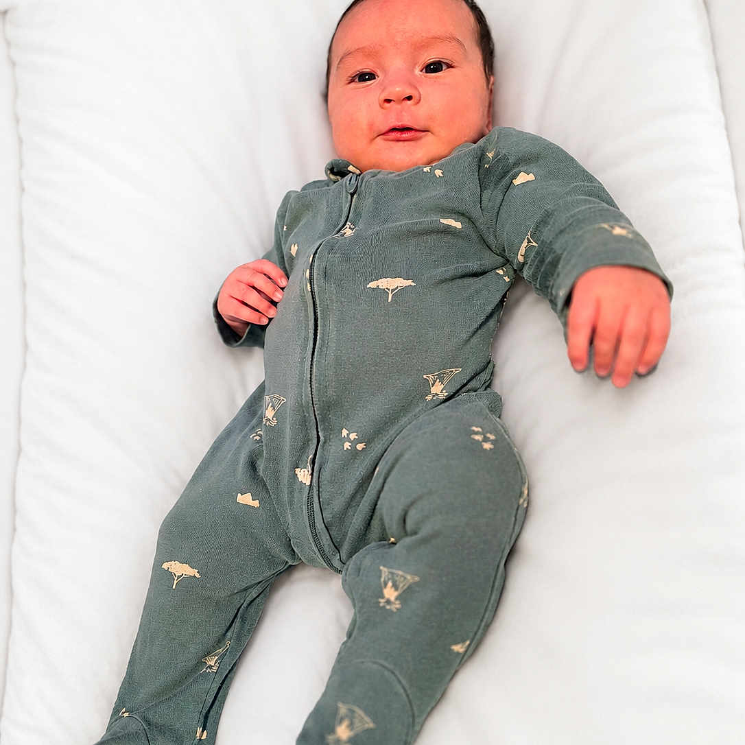 Luciano Rivera is registered to the contest to win money with this photo: baby, infant, onesie, green_clothing, sleepwear, cushion, white_background, face, hand, foot, lying_down, soft_texture, sleeping_area, portrait, child, young_baby, cozy, comfortable, cute, expression
