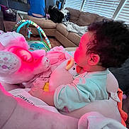 Kinsley is registered to the contest to win money with this photo: baby, plush_toy, blanket, couch, living_room, child, soft_toy, furniture, curtains, window, person, home, interior, childhood, cozy, seated, indoors, cute, comfort, relaxing
