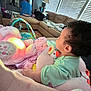 Kinsley joined the competition — help win amazing prizes! baby, child, plush_toy, blanket, couch, living_room, person, light, soft_toys, curly_hair, indoor, window_blinds, wooden_floor, casual_clothing, seated_adult, colorful, pink, green, comfort, home