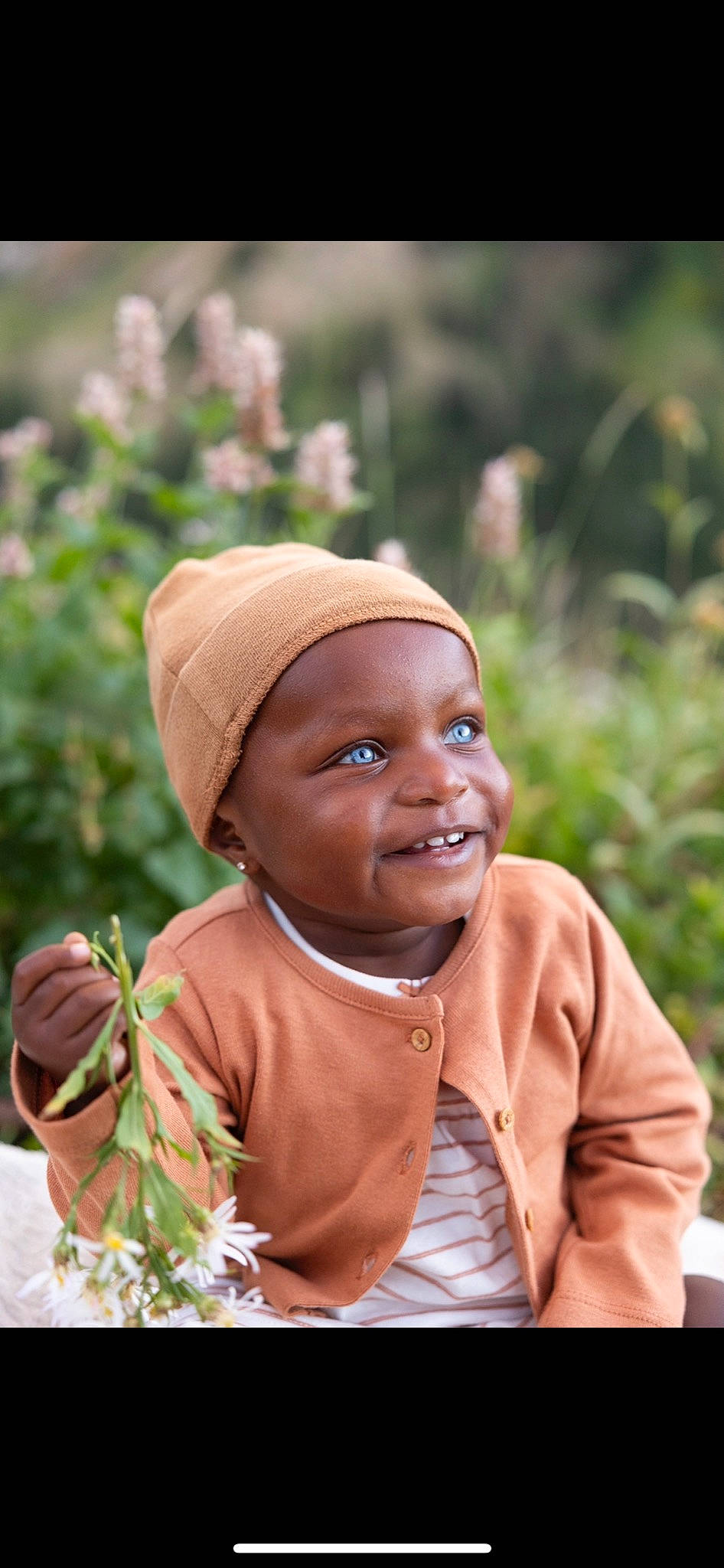 Naomi is registered to the contest to win money with this photo: adaptation, baby, child, event, fashion_accessory, grass, happy, headwear, jewellery, joy, laugh, people, people_in_nature, person, photograph, plant, sitting, skin, smile, toddler