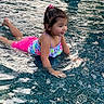 child, girl, swimming_pool, water, swimsuit, playing, smiling, summer, outdoor, fun, recreation, wet, hair_tie, young, splash, leisure, kid, happy, activity, portrait