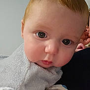 Erik is registered to the contest to win money with this photo: baby, infant, child, portrait, close_up, face, blue_eyes, blond_hair, serious_expression, wide_eyes, blanket, wrapped, cozy, indoor, adult, caregiver, arms, head, photography, cute