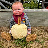 Demitri is registered to the contest to win money with this photo: baby, child, infant, pumpkin, autumn, harvest, outdoor, farm, rustic, wagon, wood, sitting, portrait, smiling, blue_eyes, boots, clothing, scarf, grass, fall
