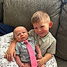 baby, child, couch, cushion, infant, person, sibling, smile, sitting, tie, young_child, cute, indoor, plaid_shirt, sock, fabric, portrait, happy, family, love