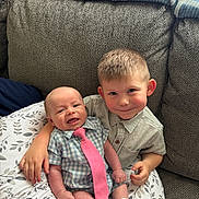 Brayden is registered to the contest to win money with this photo: baby, child, smiling, boy, tie, shirt, couch, blanket, pillow, indoors, family, cute, sitting, happy, portrait, siblings, clothing, home, candid, affection