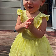 Rhyea is registered to the contest to win money with this photo: child, toddler, girl, yellow_dress, pigtails, hair_bows, clapping, smile, outdoors, wooden_deck, barefoot, sunlight, doorway, house_siding, portrait, cute, happy, summer, dress, one_person