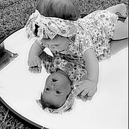 Rhyea is registered to the contest to win money with this photo: baby, infant, mirror, reflection, headband, floral_dress, grass, outdoor, lying_down, portrait, black_and_white, hands, face, hair, cute, toddler, playtime, closeup, babyclothes, ground