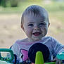 baby, child, smiling, blue_eyes, activity_walker, toy, colorful, happy, face, infant, clothing, hand, outdoor, blurred_background, person, cute, young_child, playful, portrait, seated