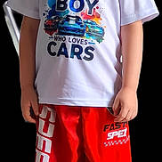 Georgie is registered to the contest to win money with this photo: boy, casual_clothing, child, colorful, cute, fashion, feet, footwear, full_body, happy, indoor, isolated, portrait, red_shorts, short_hair, smiling, sneakers, standing, text_on_clothing, white_tshirt