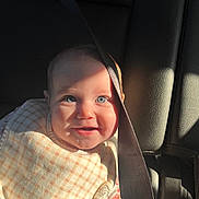 Anastasia is registered to the contest to win money with this photo: baby, child, car_seat, seat_belt, smile, blue_eyes, sunlight, shadow, bib, clothing, infant, cute, happy, sitting, portrait, car_interior, hand, face, young_child, sunlight_shadow