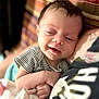 Violet is registered to the contest to win money with this photo: baby, infant, smiling, sleepy, striped_clothing, blanket, cuddling, closeup, indoor, person, portrait, soft_light, comfort, resting, head, hand, adult, tattoo, fabric, cozy