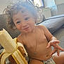 banana, bare_chest, child, closeup, couch, curly_hair, cute, diaper, eating, fruit, happy, home, living_room, necklace, playful, portrait, sitting, smile, snack, toddler