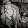 Noah a rejoint le concours — aidez-le/la à gagner de superbes lots ! baby, child, hat, checkered_clothing, pants, suspenders, armchair, miniature_table, globe, bottle, laptop, wooden_floor, monochrome, portrait, indoors, serious_expression, small_furniture, cute, vintage_style, sitting