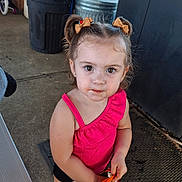 Ashlyn is registered to the contest to win money with this photo: casual, child, concrete_floor, curious_expression, cute, daylight, eyes, face, girl, hair_bows, messy_face, outdoor, person, pigtails, pink_clothing, snack, standing, summer, toddler, trash_bins