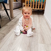 Alice participe au concours pour gagner de l'argent avec cette photo : baby, child, infant, floor, bib, pink, toy, crib, chair, wooden_floor, home_interior, furniture, smiling, cute, sitting, white_clothes, happy, indoor, person, flooring