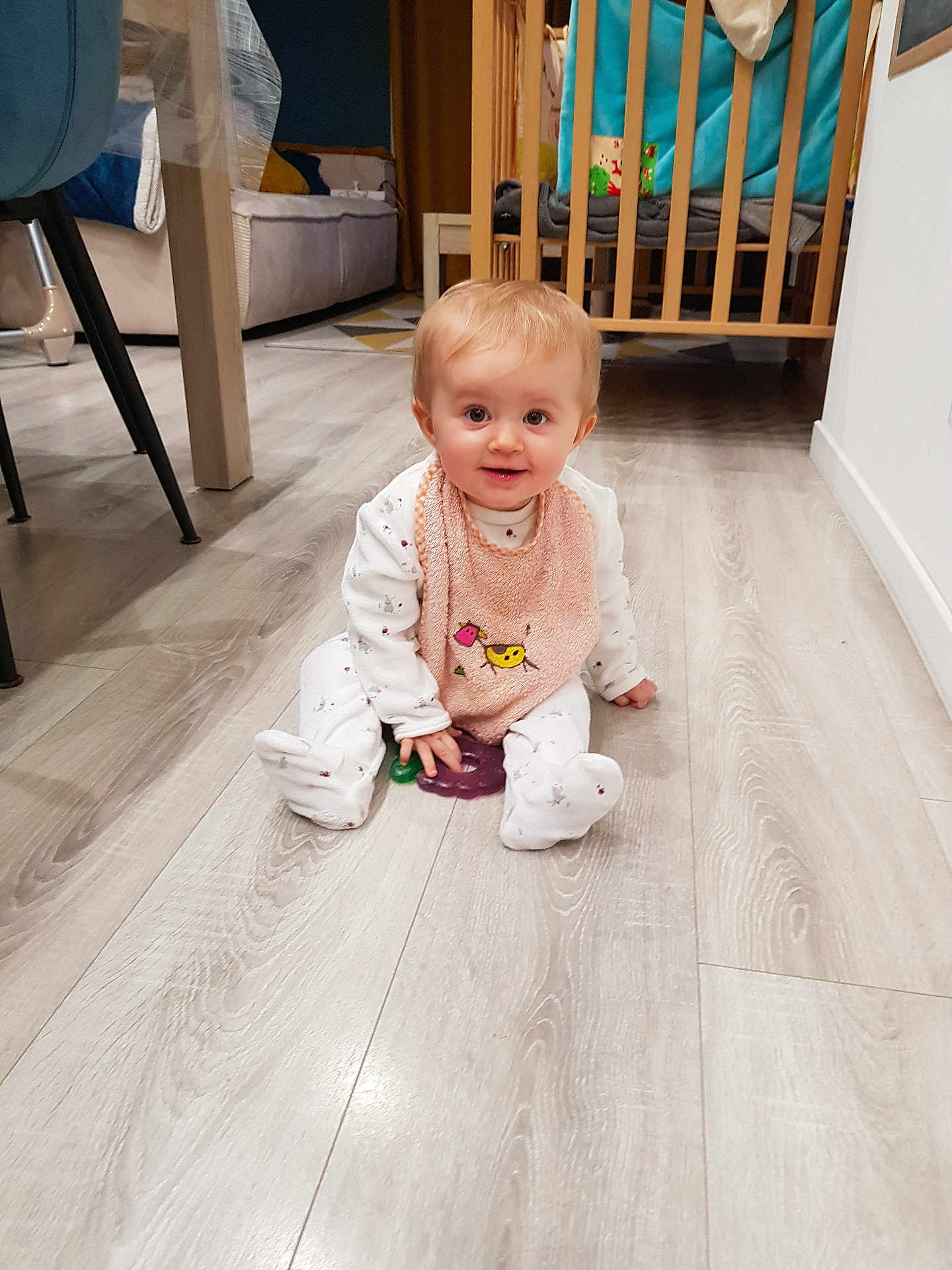 Alice participe au concours pour gagner de l'argent avec cette photo : baby, child, infant, floor, bib, pink, toy, crib, chair, wooden_floor, home_interior, furniture, smiling, cute, sitting, white_clothes, happy, indoor, person, flooring