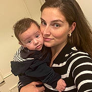 Sohan participe au concours pour gagner de l'argent avec cette photo : woman, baby, child, holding, indoor, striped_clothing, black_and_white, portrait, face, person, close_up, eyewear, gold_earrings, curly_hair, long_hair, casual_clothing, door, hand, soft_lighting, selfie