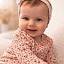 baby, child, smiling, headband, blue_eyes, pink_top, patterned_clothing, denim_jeans, sitting, portrait, closeup, happy, indoor, soft_light, cute, infant, face, person, cozy, warm_colors