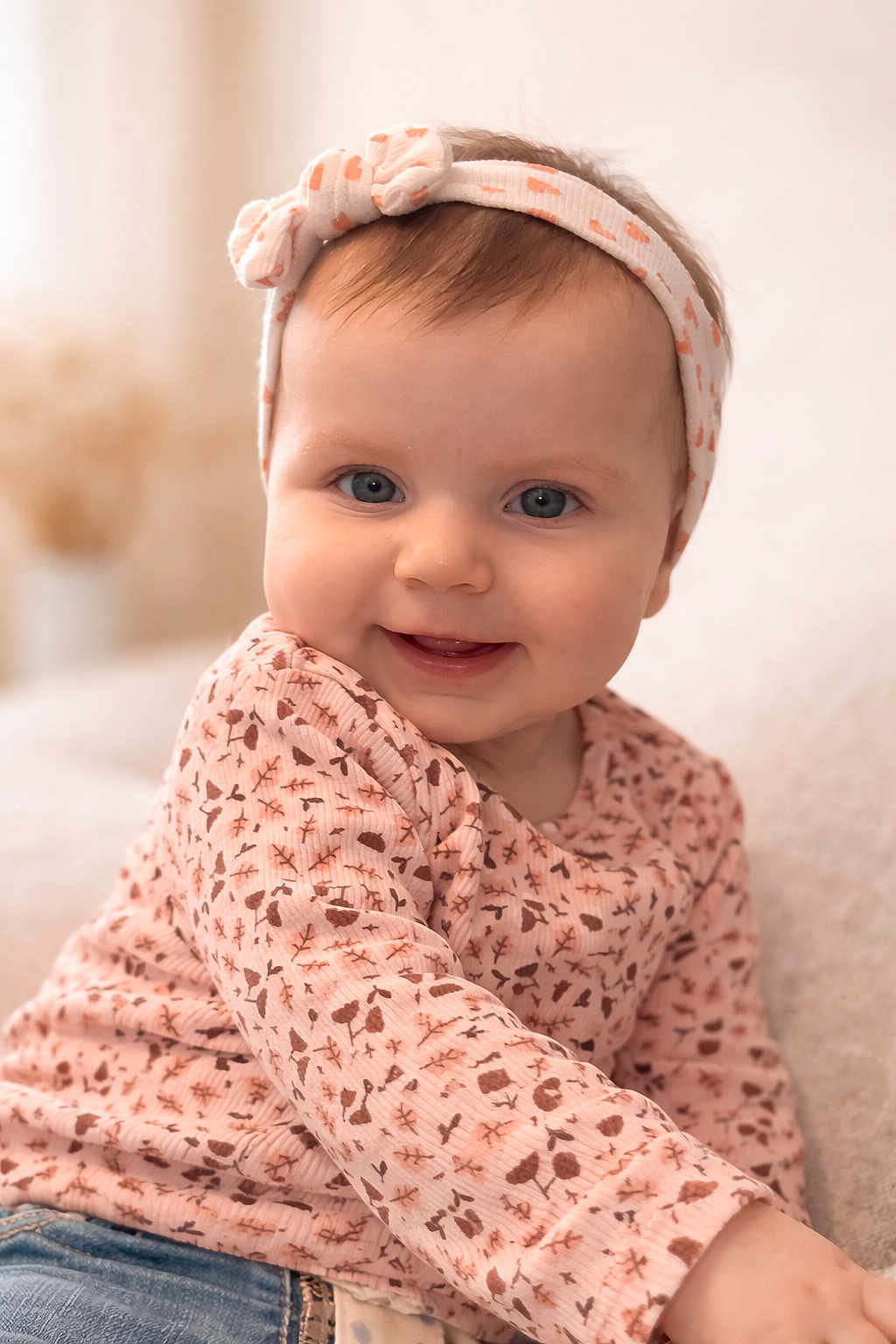 Ambre participe au concours pour gagner de l'argent avec cette photo : baby, child, smiling, headband, blue_eyes, pink_top, patterned_clothing, denim_jeans, sitting, portrait, closeup, happy, indoor, soft_light, cute, infant, face, person, cozy, warm_colors
