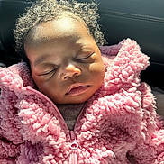 Laylani is registered to the contest to win money with this photo: baby, sleeping, pink_jacket, curly_hair, fluffy, close_up, child, soft_light, cozy, peaceful, portrait, infant, warm_clothing, cute, face, relaxation, indoors, young_child, toddler, adorable