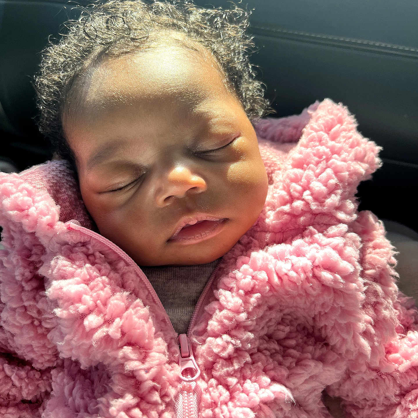 Laylani is registered to the contest to win money with this photo: baby, sleeping, pink_jacket, curly_hair, fluffy, close_up, child, soft_light, cozy, peaceful, portrait, infant, warm_clothing, cute, face, relaxation, indoors, young_child, toddler, adorable