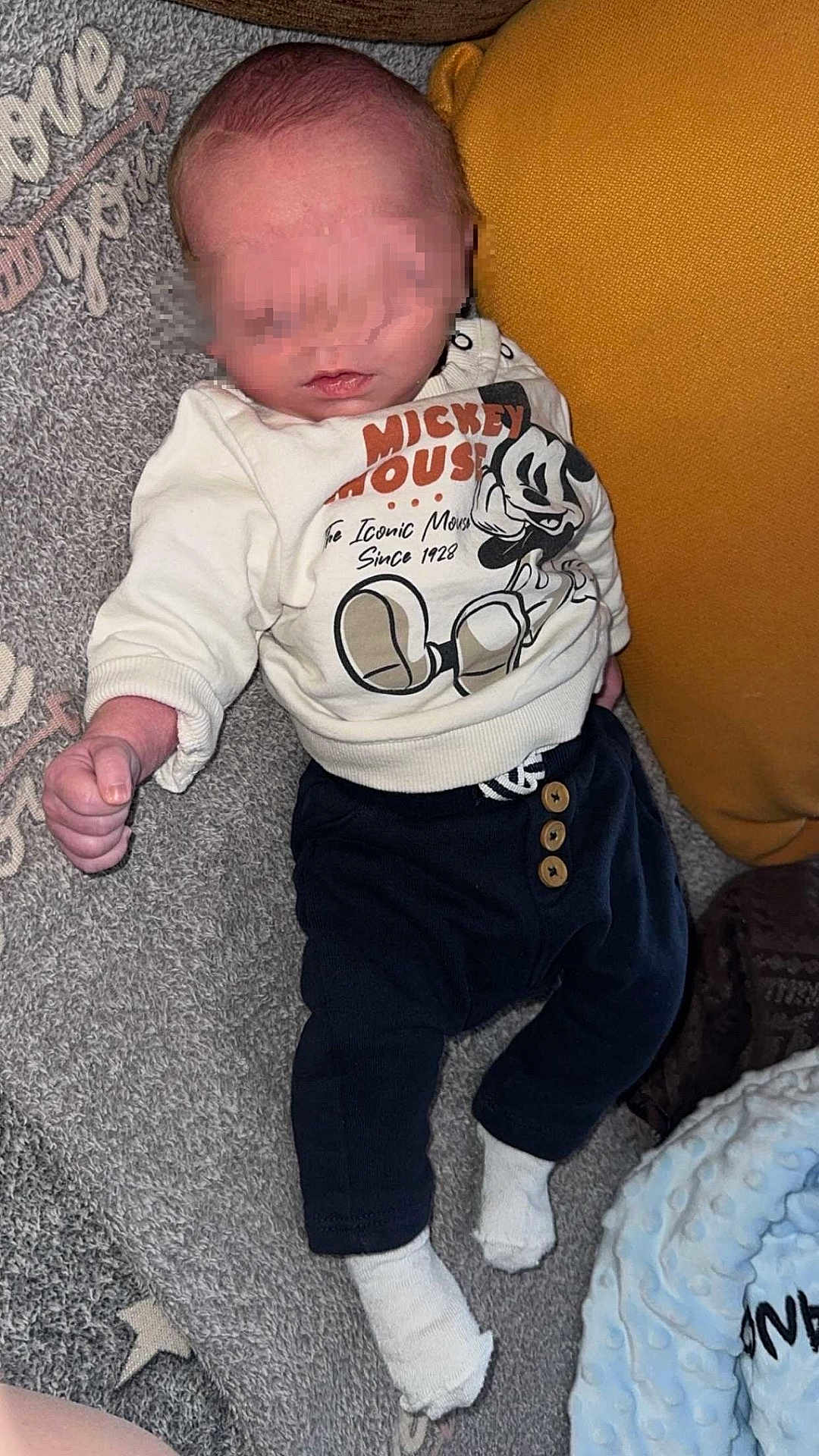 Djoulyano a rejoint le concours — aidez-le/la à gagner de superbes lots ! baby, infant, mickey_mouse, sweater, pants, socks, carpet, pillow, blanket, lying_down, indoor, child, cute, soft_texture, clothing, person, newborn, resting, comfort, casual
