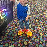 Jacyiah is registered to the contest to win money with this photo: toddler, child, roller_skates, arcade, game_machine, colorful_carpet, blue_shirt, jeans, indoor, play, curious, young_child, person, feet, hand, light, floor, toy, entertainment, amusement