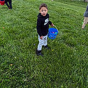 Zaidyn Wilkinson joined the competition — help win amazing prizes! child, grass, bucket, outdoor, field, easter_eggs, person, holding, toy, activity, greenery, casual, clothing, hoodie, footwear, play, event, spring, celebration, fun