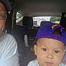 adult, baby, car, car_seat, casual_clothing, child, curious, daylight, face, hat, headwear, human, indoor, person, portrait, purple_cap, seat, toddler, vehicle_interior, window