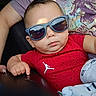 adult_arm, baby, blanket, casual, casual_clothing, child, closeup, cute, fashion, hand, holding, indoor, person, portrait, red_shirt, relaxed, seat, serious_expression, sunglasses, toddler