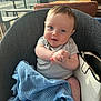baby, child, smile, blue_blanket, knitted_blanket, chair, indoor, purse, white_purse, person, happy, face, hands, clothing, window, daylight, seated, cute, infant, portrait