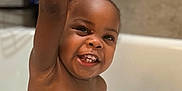 Kyren is registered to the contest to win money with this photo: toddler, bathtub, bath, child, smiling, happy, water, soap, arm, raised_hand, teeth, skin, face, indoor, tile, bathroom, toy, blurred_background, cute, playful