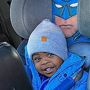 Kyren is registered to the contest to win money with this photo: child, toddler, car_seat, blue_jacket, gray_beanie, batman_cover, car_interior, smiling, seatbelt, apple, happy, young_child, portrait, winter_clothing, cute, kid, car_window, daylight, seat_headrest, travel