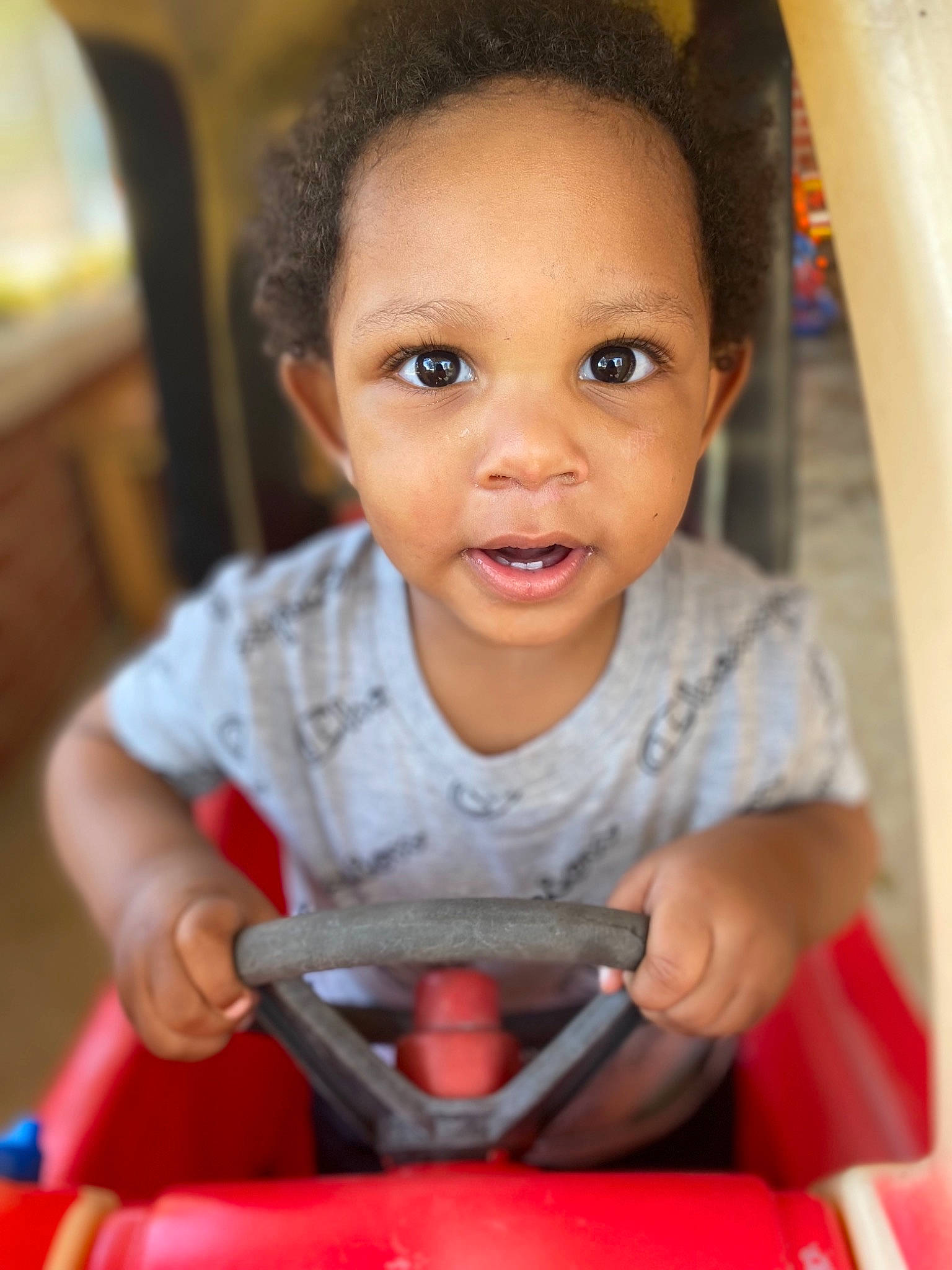 Antwain is registered to the contest to win money with this photo: baby, cheek, child, chin, eyebrow, eyelash, fun, happy, iris, lip, mouth, nose, organ, person, photograph, red, riding_toy, skin, smile, standing