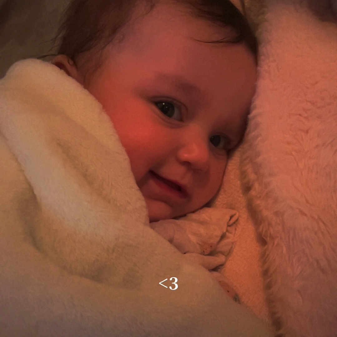 Solaya a rejoint le concours — aidez-le/la à gagner de superbes lots ! baby, bedding, blanket, cheek, child, closeup, cozy, cuddly, cute, eyes, face, glasses, hair, indoor, infant, low_light, partially_visible_person, smile, soft_texture, tucked_in