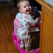 Ryelle joined the competition — help win amazing prizes! baby, child, walker, floral_onesie, smiling, happy, indoors, wooden_floor, furniture, cabinet, chair, person, standing, toy, cute, playtime, home, flooring, footwearless, infant